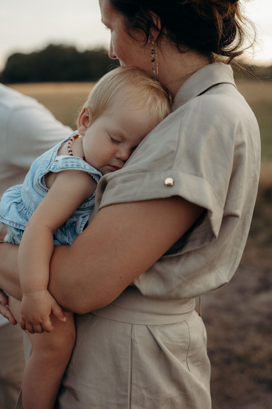 Moeder houdt haar slapende baby tegen zich aan in een veld